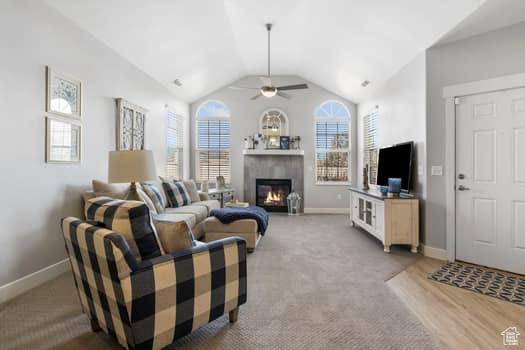 Living room featuring a wealth of natural light, vaulted ceiling, ceiling fan, and light carpet