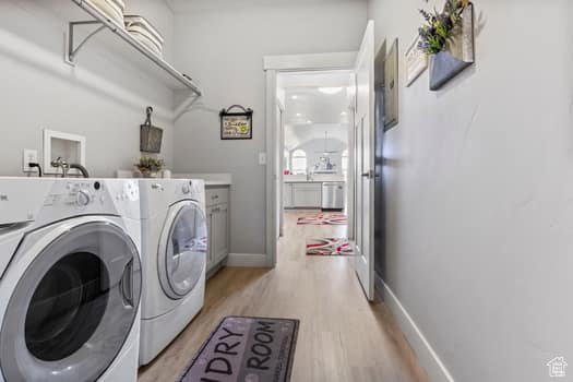 Laundry area featuring light hardwood / wood-style flooring, cabinets, and washer and clothes dryer
