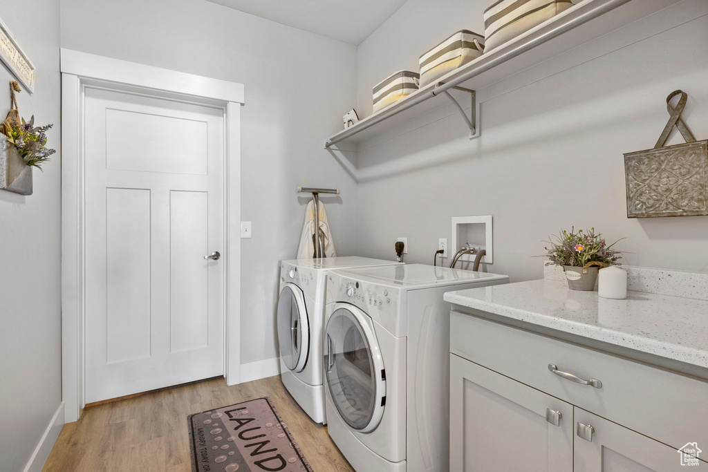 Laundry room featuring light hardwood / wood-style floors, washer and clothes dryer, washer hookup, hookup for an electric dryer, and cabinets