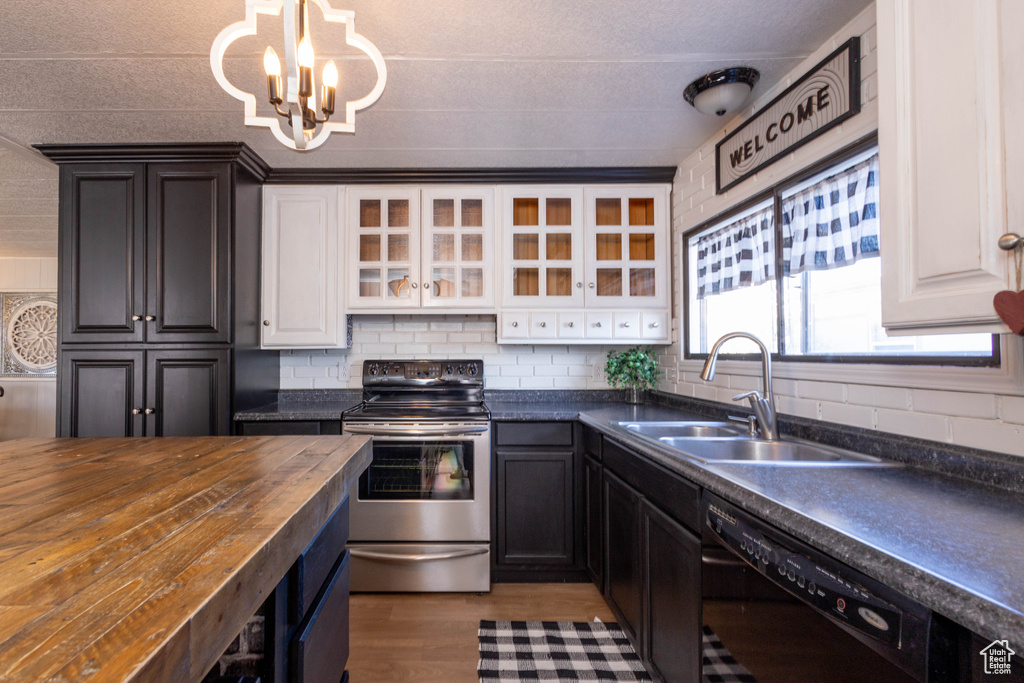 Kitchen featuring white cabinetry, a notable chandelier, stainless steel electric range, and butcher block countertops