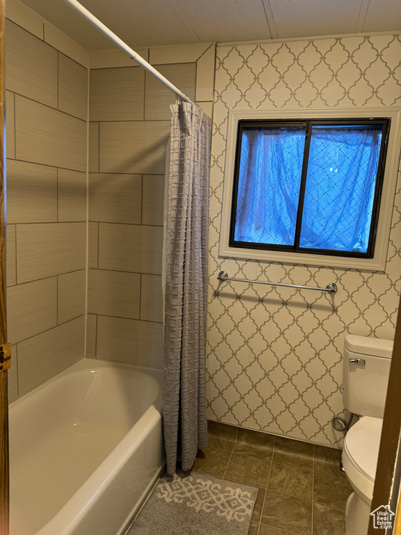Bathroom featuring tile floors, shower / bath combination with curtain, and toilet