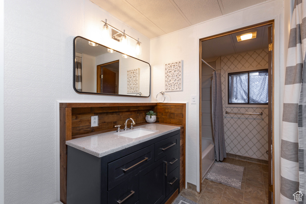Bathroom with backsplash, tile floors, vanity, and shower / tub combo with curtain