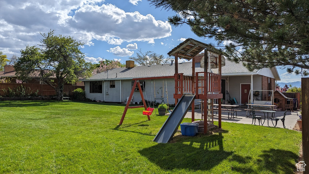 Exterior space featuring a playground, a patio area, and a lawn