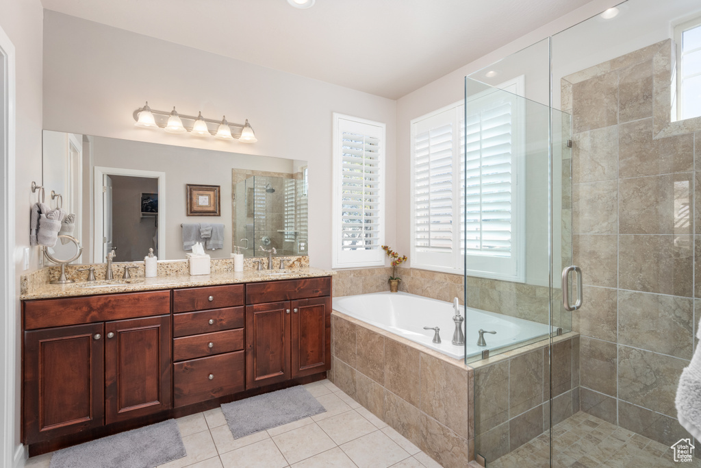 Bathroom with plenty of natural light, shower with separate bathtub, tile floors, and double sink vanity