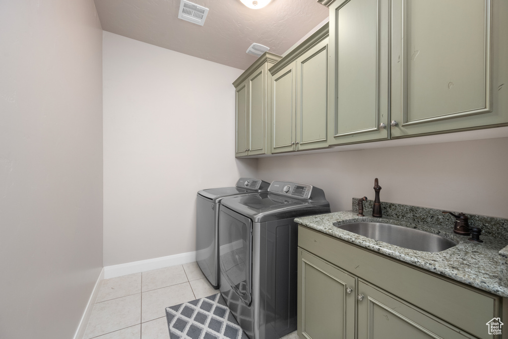 Laundry room with cabinets, sink, washing machine and dryer, and light tile flooring