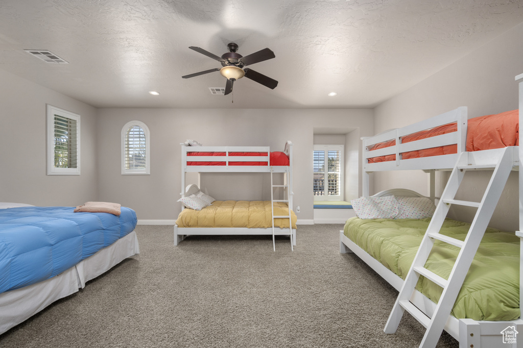 Bedroom with multiple windows, ceiling fan, and carpet floors