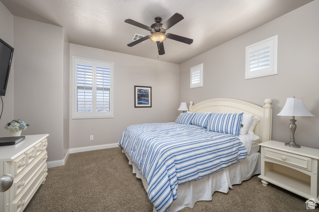 Bedroom with ceiling fan and dark colored carpet