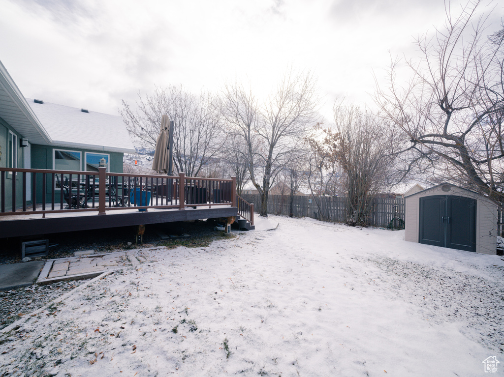 Snowy yard with a shed and a wooden deck