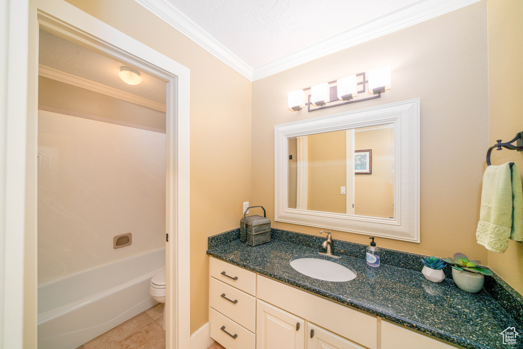 Full bathroom with shower / bathtub combination, toilet, tile flooring, large vanity, and crown molding