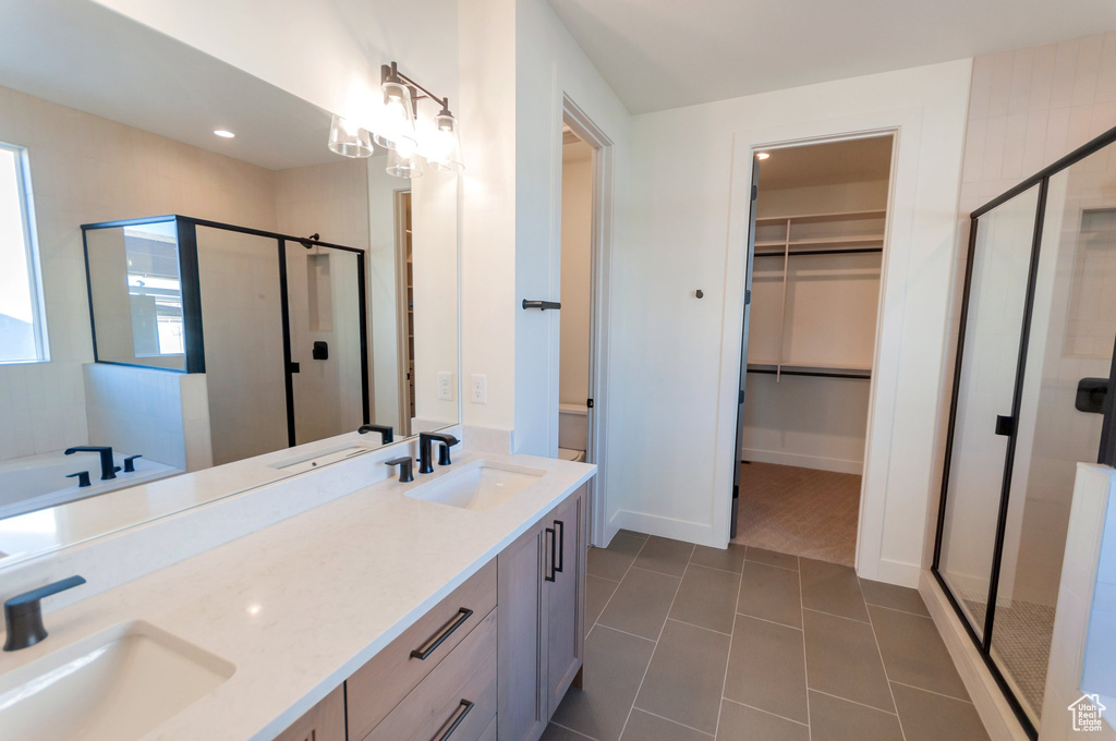 Bathroom featuring dual bowl vanity, tile flooring, and separate shower and tub