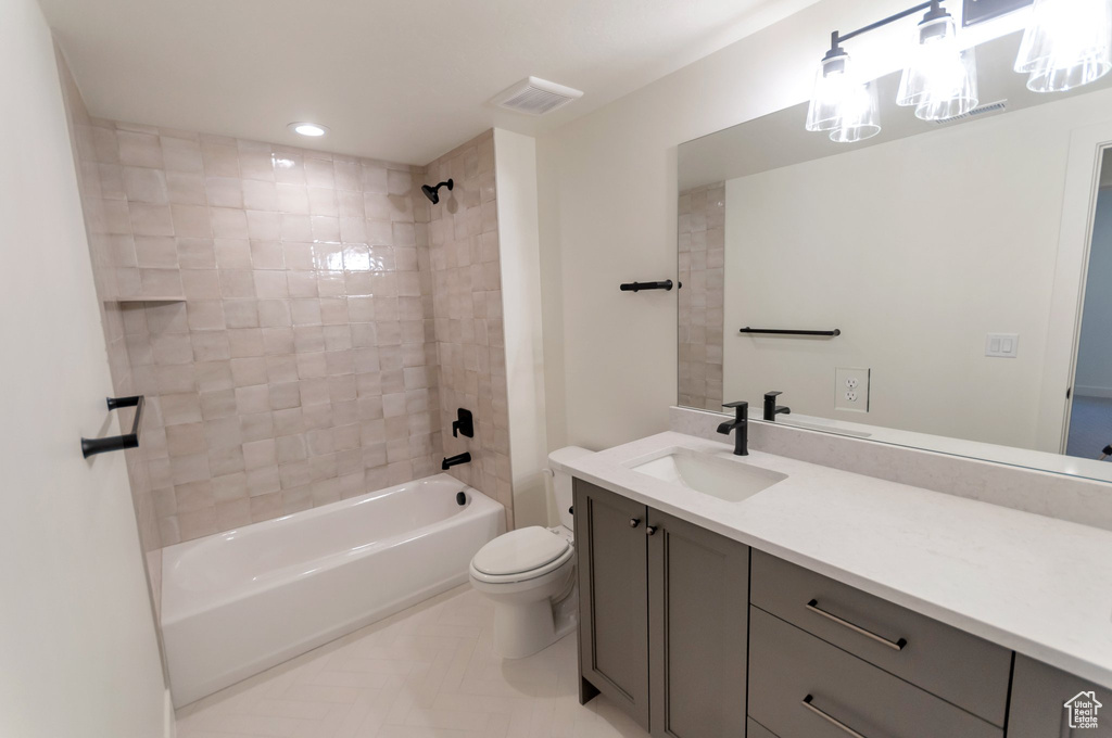 Full bathroom featuring tile flooring, toilet, tiled shower / bath, and oversized vanity