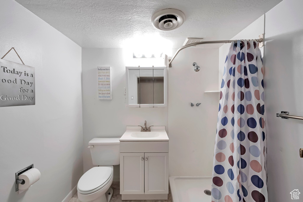 Bathroom featuring tile floors, vanity, toilet, and a textured ceiling