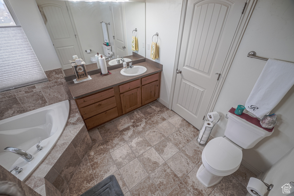 Bathroom with vanity, toilet, tiled tub, and tile floors