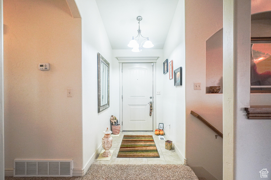 Doorway with a chandelier and light tile flooring