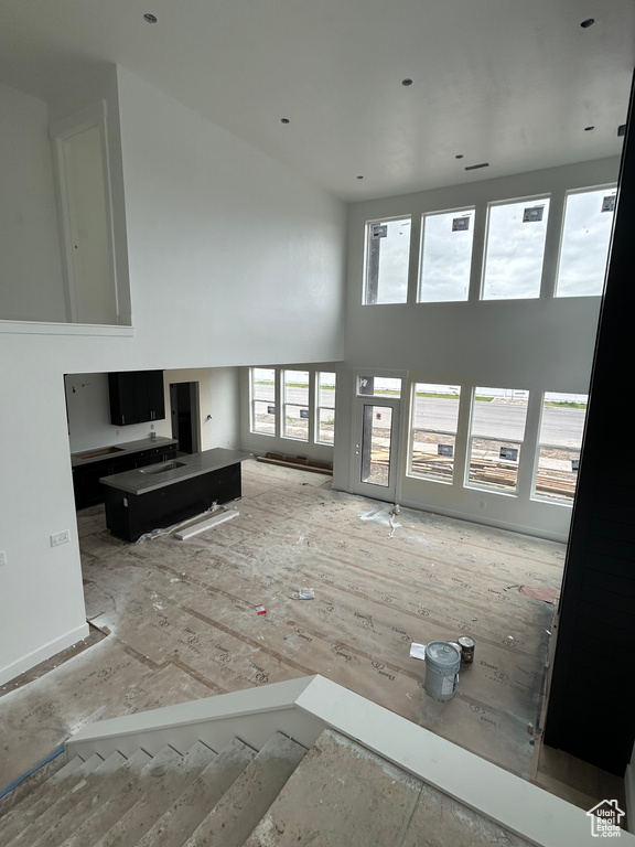 Unfurnished living room featuring a towering ceiling