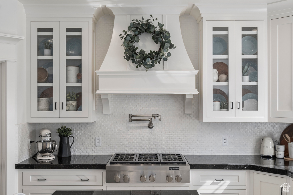 Interior space featuring tasteful backsplash, stainless steel gas cooktop, dark stone countertops, and white cabinetry