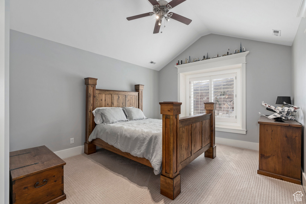 Bedroom with vaulted ceiling, light colored carpet, and ceiling fan
