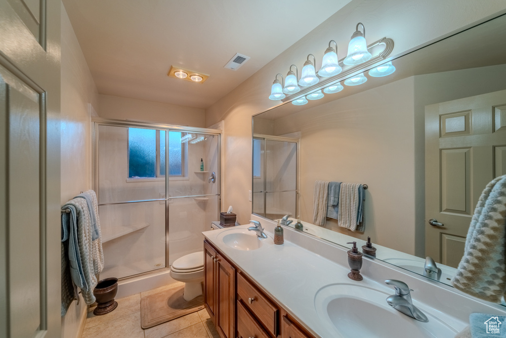 Bathroom with a shower with shower door, tile floors, large vanity, toilet, and dual sinks