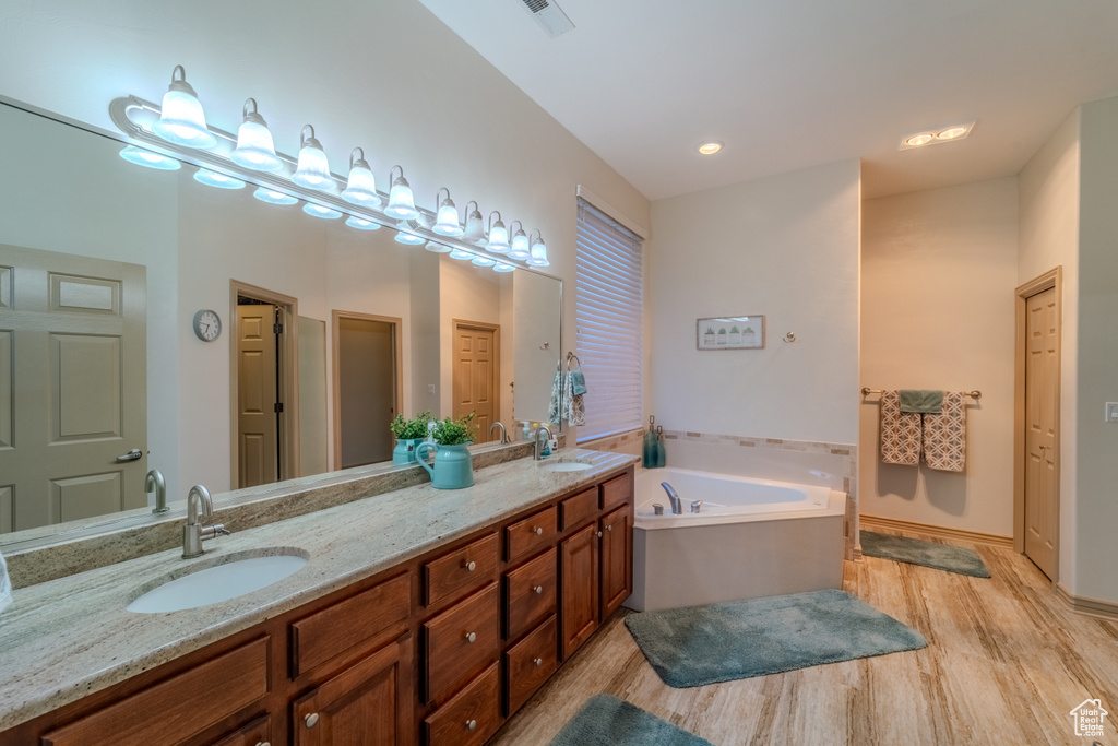 Bathroom featuring double sink vanity, a bath to relax in, and hardwood / wood-style flooring