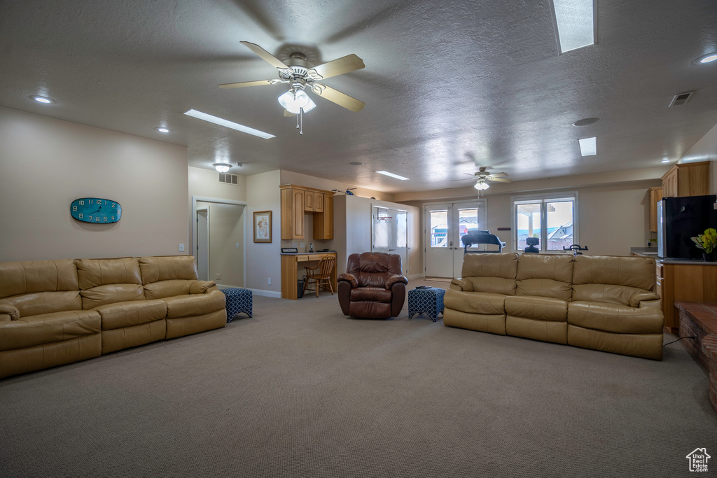 Living room with carpet flooring, a skylight, and ceiling fan