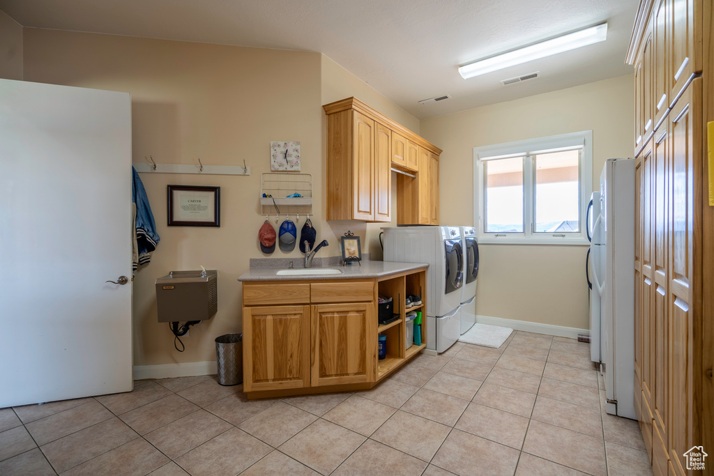 Kitchen featuring light tile floors, washer and clothes dryer, sink, and white fridge