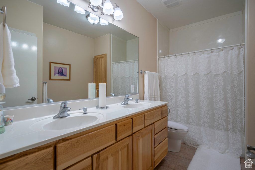 Bathroom featuring oversized vanity, tile floors, toilet, and double sink