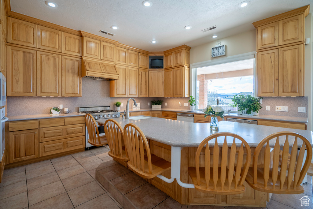 Kitchen featuring premium range hood, sink, dishwasher, and light tile floors