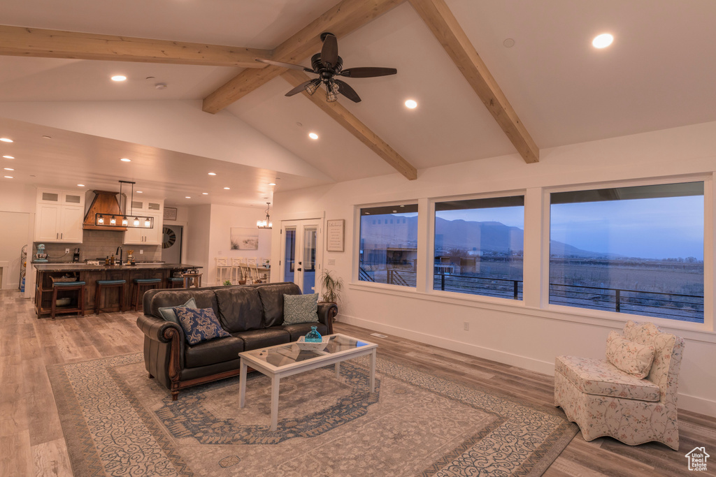 Living room with a mountain view, ceiling fan, beam ceiling, hardwood / wood-style floors, and high vaulted ceiling
