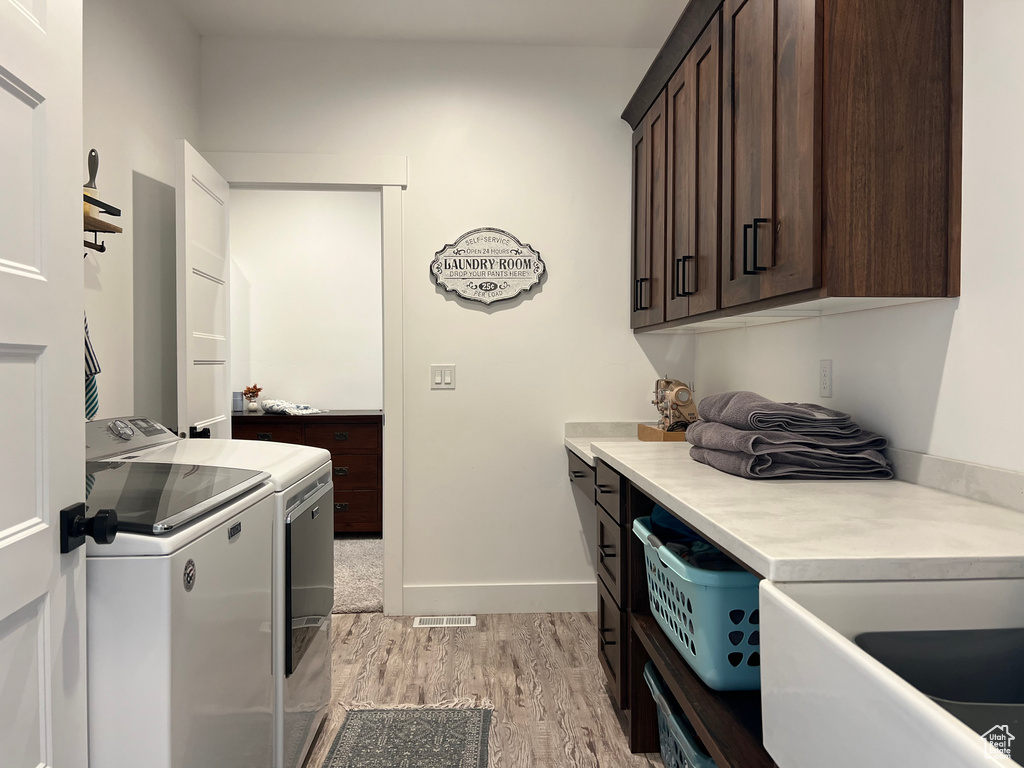 Laundry room featuring cabinets, washer and clothes dryer, and light hardwood / wood-style floors