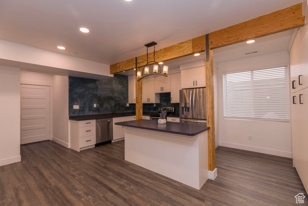 Kitchen featuring appliances with stainless steel finishes, decorative light fixtures, white cabinetry, and dark hardwood / wood-style floors
