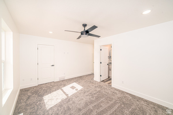 Interior space featuring light carpet, ensuite bath, and ceiling fan