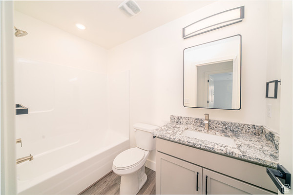 Full bathroom featuring vanity, bathing tub / shower combination, hardwood / wood-style floors, and toilet