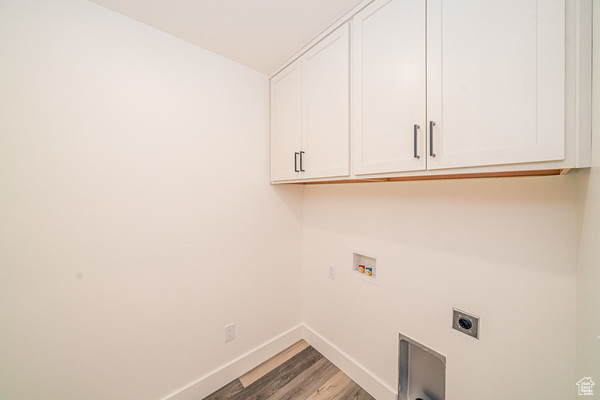 Washroom with hookup for an electric dryer, cabinets, hookup for a washing machine, and hardwood / wood-style floors