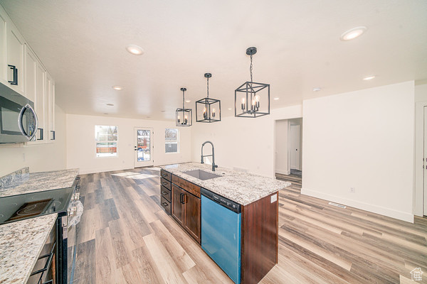 Kitchen featuring sink, an island with sink, light stone countertops, light hardwood / wood-style flooring, and stainless steel appliances
