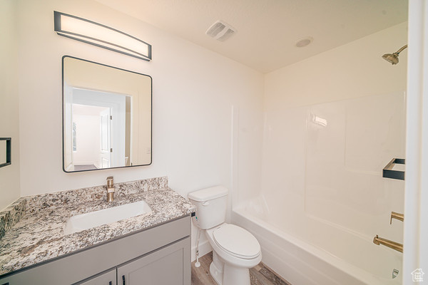 Full bathroom featuring vanity, toilet, tub / shower combination, and hardwood / wood-style floors