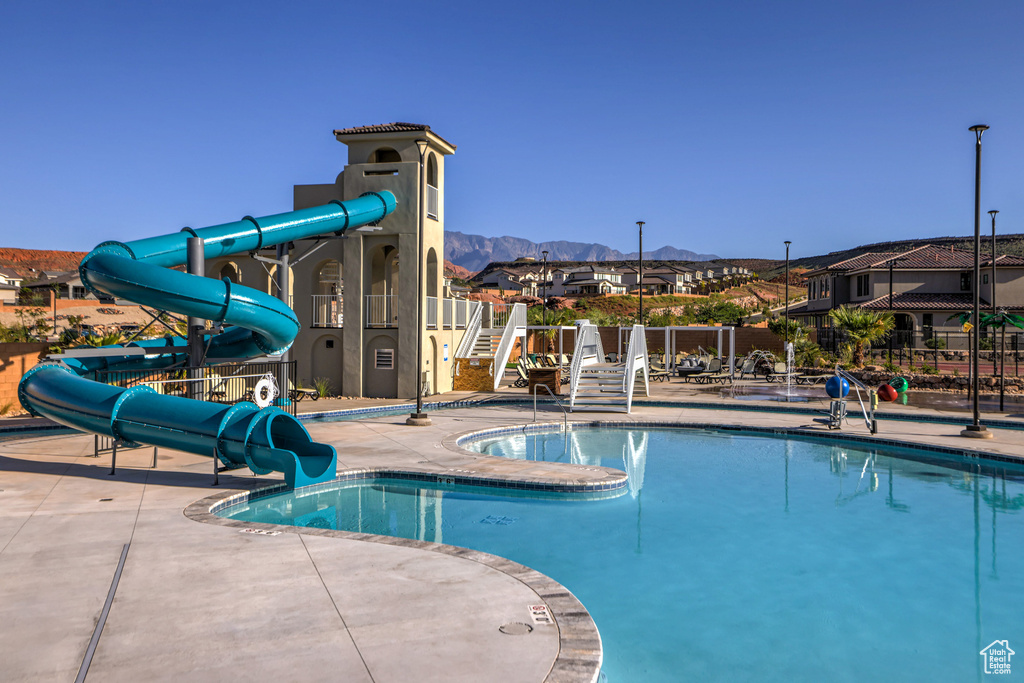 View of pool featuring a water slide, a patio area, and a mountain view