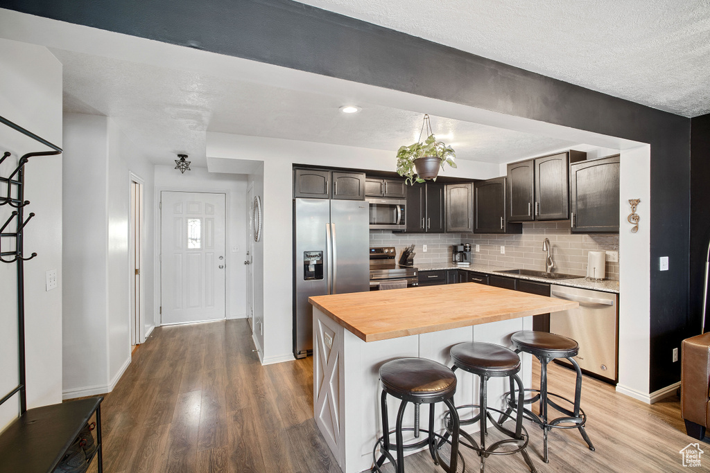 Kitchen featuring wood-type flooring, stainless steel appliances, sink, and a kitchen island