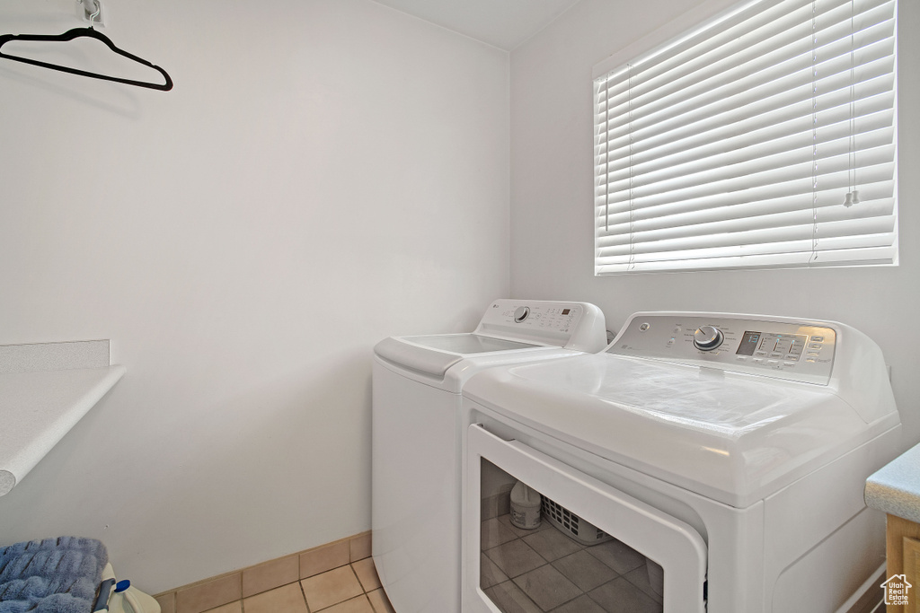 Laundry area with washer and clothes dryer, light tile floors, and a healthy amount of sunlight