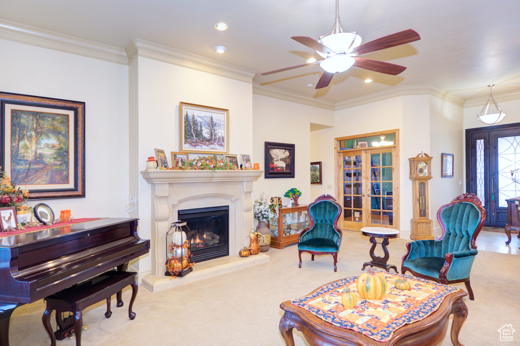 Living room featuring french doors, light colored carpet, ornamental molding, and ceiling fan