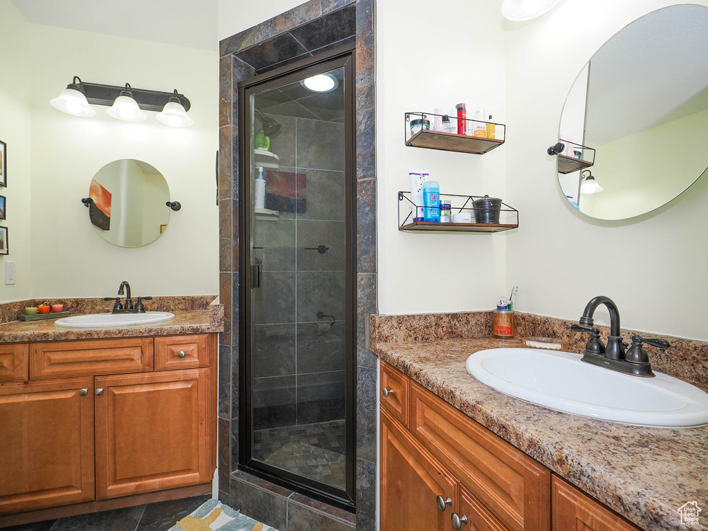 Bathroom with a shower with shower door, tile floors, and vanity