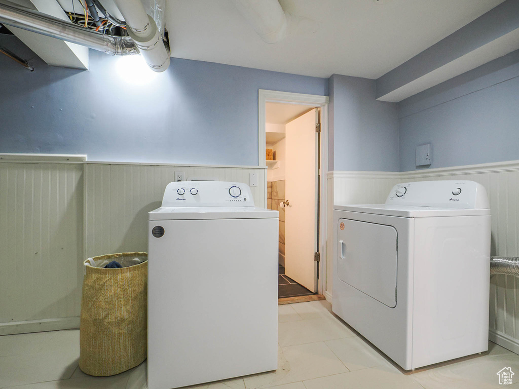 Laundry area featuring light tile floors and washing machine and clothes dryer
