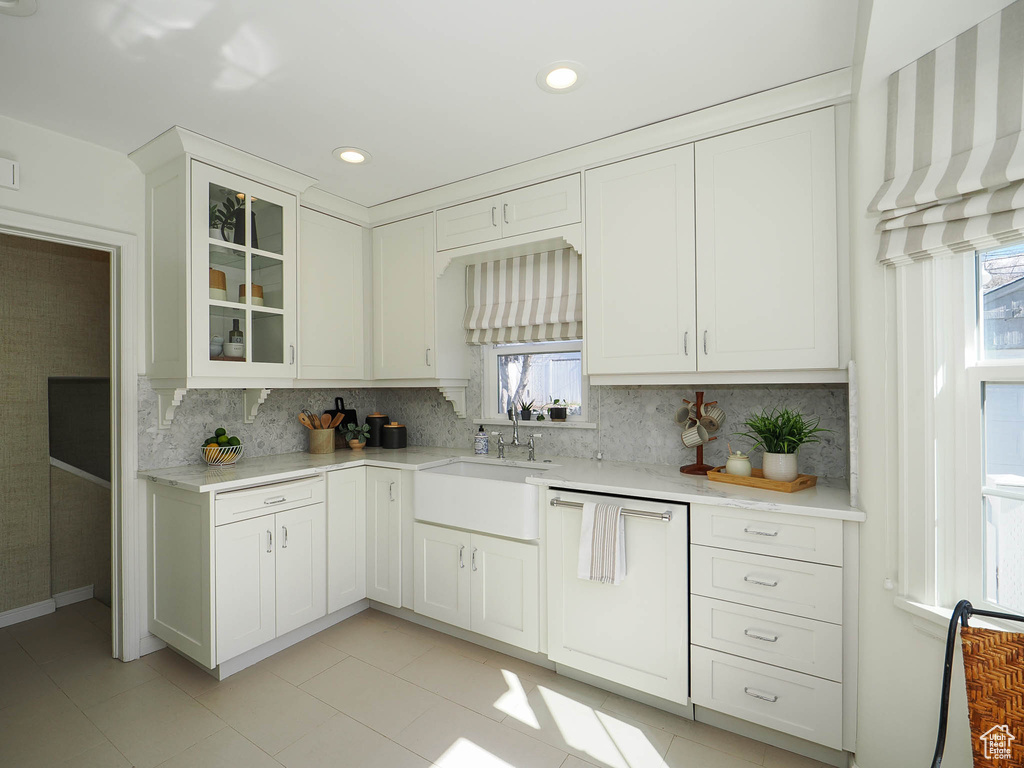 Kitchen featuring a wealth of natural light, light tile floors, and white cabinets