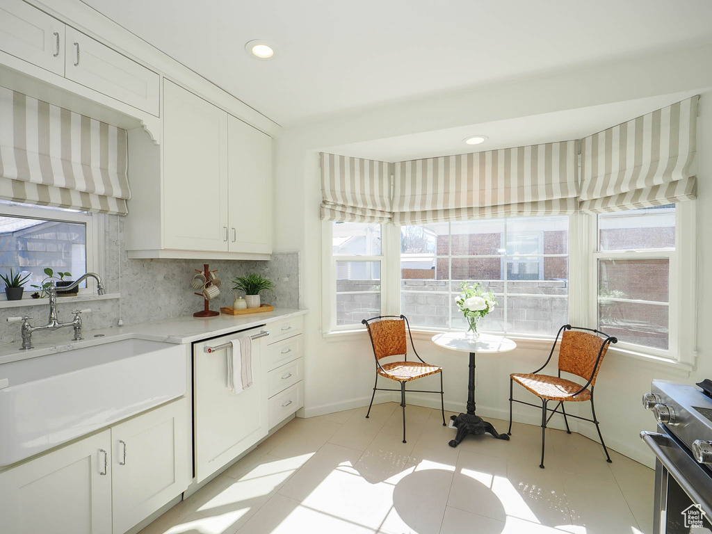 Kitchen with white cabinets, light tile flooring, a wealth of natural light, and white dishwasher