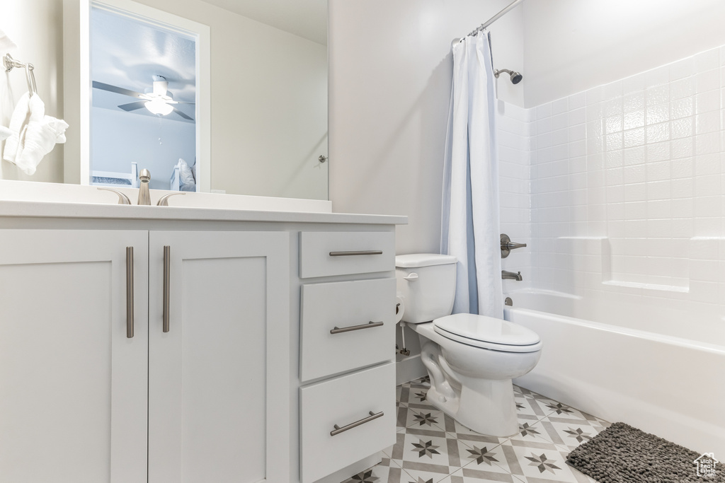 Full bathroom with vanity with extensive cabinet space, ceiling fan, toilet, tile floors, and shower / tub combo with curtain