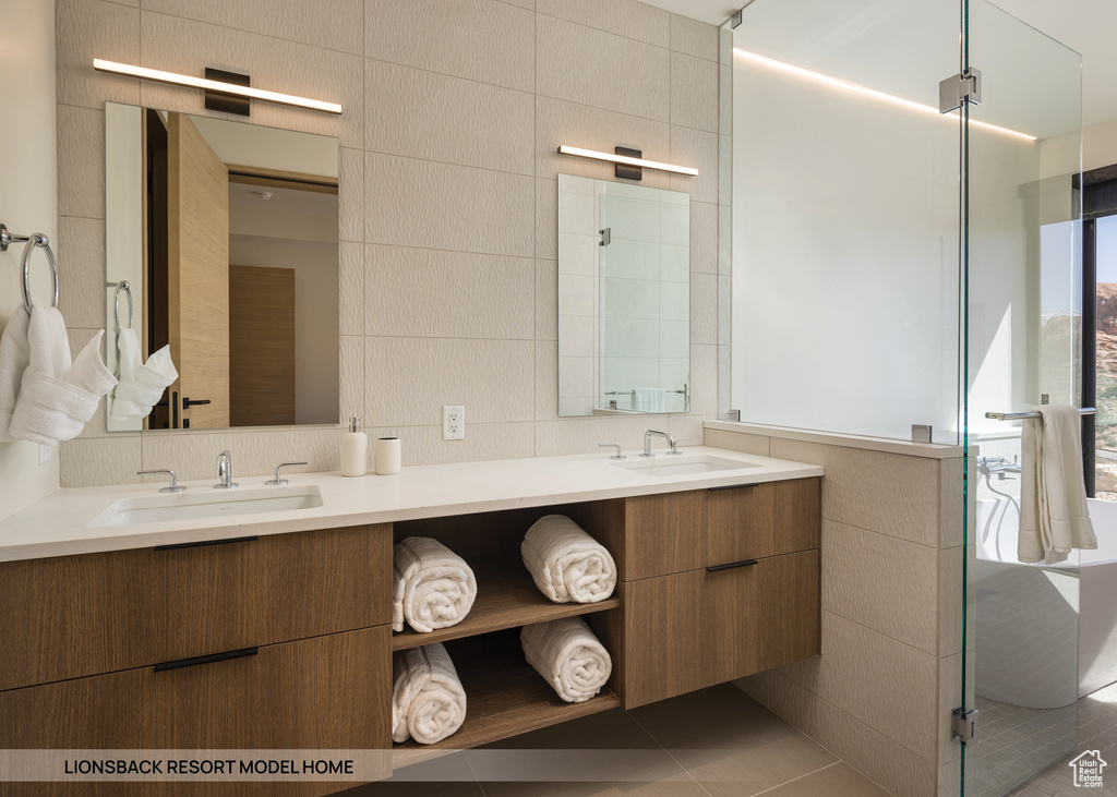 Bathroom featuring tile flooring, double sink vanity, and tile walls