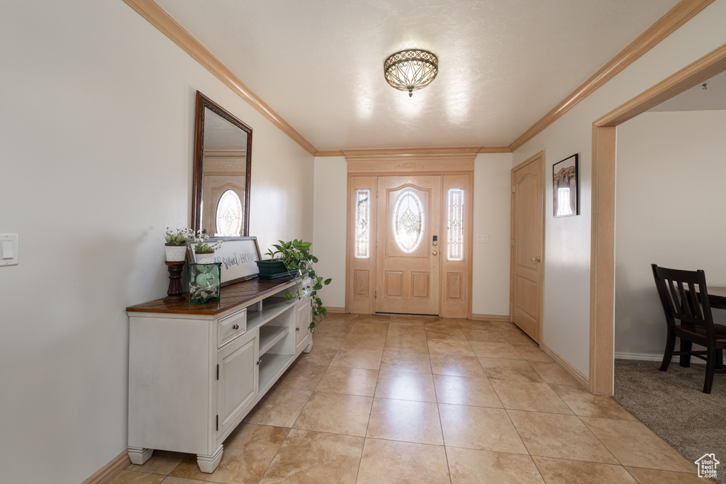 Foyer featuring ornamental molding and light colored carpet