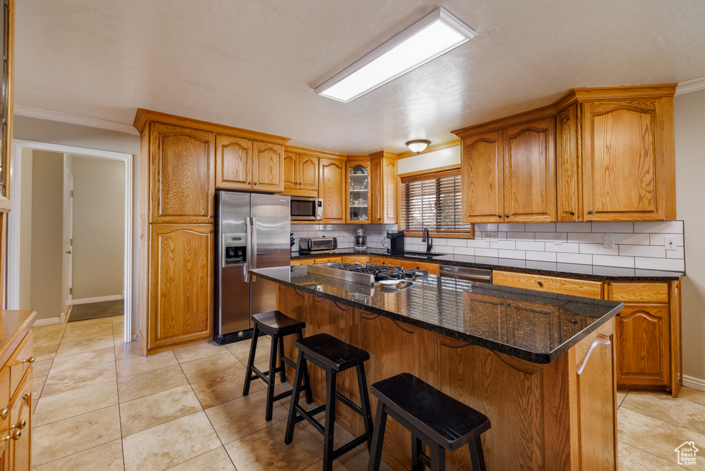 Kitchen featuring light tile flooring, a center island, stainless steel appliances, and tasteful backsplash
