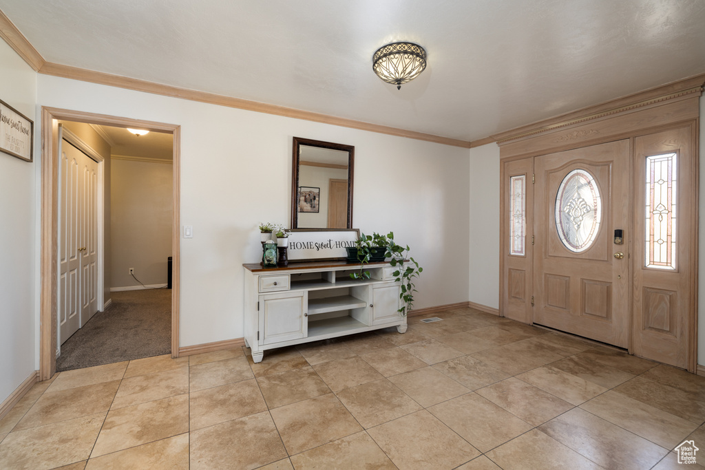 Foyer with light tile floors and crown molding