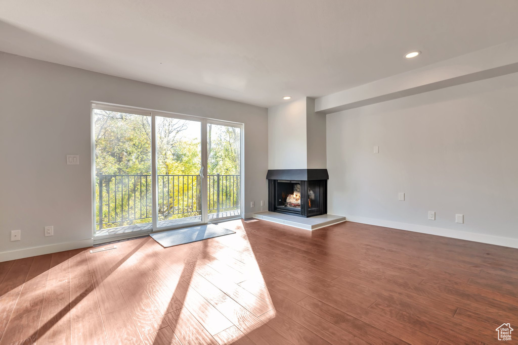 Unfurnished living room featuring hardwood / wood-style floors and a multi sided fireplace
