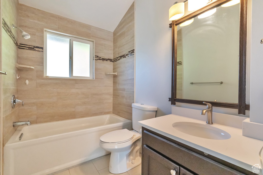 Full bathroom featuring toilet, tile flooring, large vanity, and tiled shower / bath